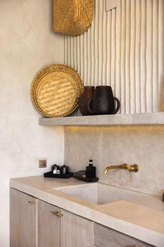 a kitchen with a sink and a basket on a shelf at The Konkret Lombok in Kuta Lombok