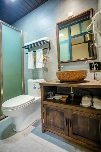 a bathroom with a toilet and a sink and a mirror at Pingyao Grand Theater Guild Hall East Garden in Pingyao