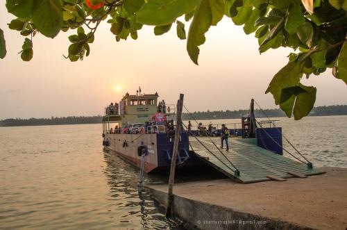 a ferry boat docked at a dock in the water at Palm Vista Vacations Barkur Udupi District in Bārkūr