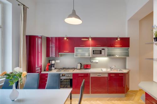 プラハにあるセリノル オールド タウン アパートメンツのキッチン(赤いキャビネット、テーブル、青い椅子付)