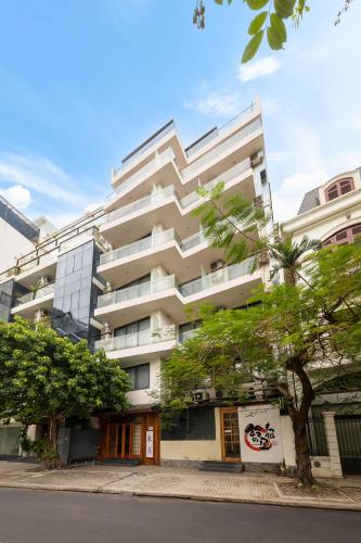 a tall white building with a tree in front of it at Azumaya Hotel Kim Ma 2 in Hanoi