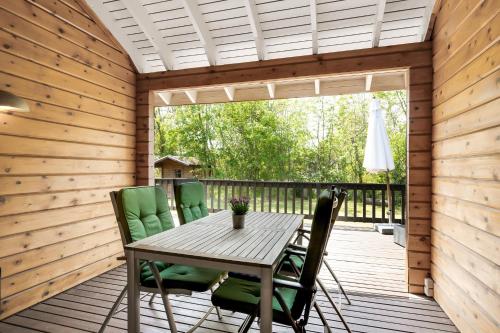a wooden patio with a table and chairs on a deck at Beautiful And Family-Friendly Holiday Home For 9 People With A Spa Bath Near Grenaa Beach in Grenå