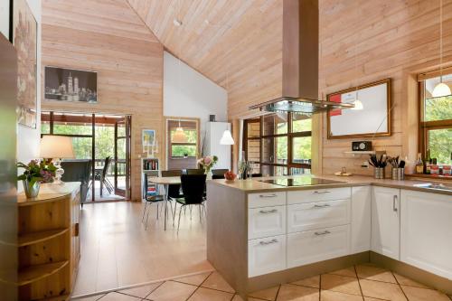 a kitchen with white cabinets and a dining room at Beautiful And Family-Friendly Holiday Home For 9 People With A Spa Bath Near Grenaa Beach in Grenå