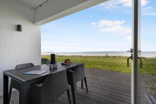 a table and chairs on a patio with a view of the ocean at Beautiful Holiday Apartment With A View Of Ebeltoft Vig And Walking Distance To The Town Center in Ebeltoft