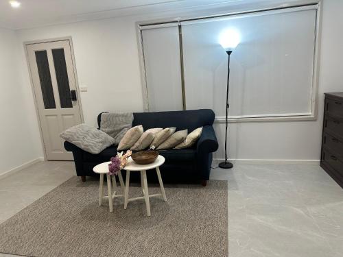 a living room with a blue couch and a table at Lovely and cosy brandnew room if no one book in other 2 rooms you willl stay by yourself in the whole house in West Hoxton