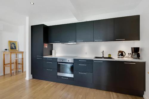 a kitchen with black cabinets and a stove at Beautiful Holiday Apartment With A View Of Ebeltoft Vig And Walking Distance To The Town Center in Ebeltoft