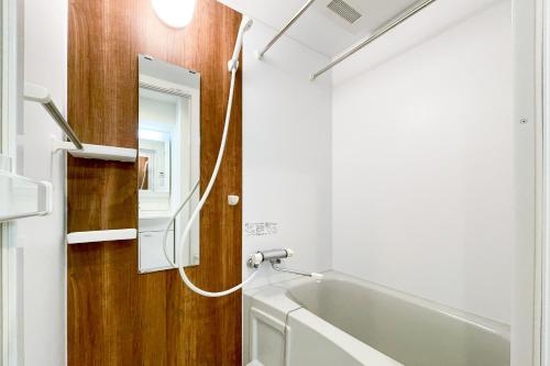 a bathroom with a bath tub and a mirror at Shin-Umeda Central Hills in Osaka