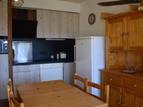 une cuisine avec une table en bois et un réfrigérateur blanc dans l'établissement Charmant T2 cabine style chalet, près du centre et télécabines, parfait pour les vacances - FR-1-580-123, à Font-Romeu-Odeillo-Via