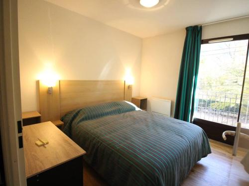 um quarto de hotel com uma cama e uma janela em Charmant T2 avec balcon, parking et lave-linge près du parc - FR-1-313-235 em Luchon