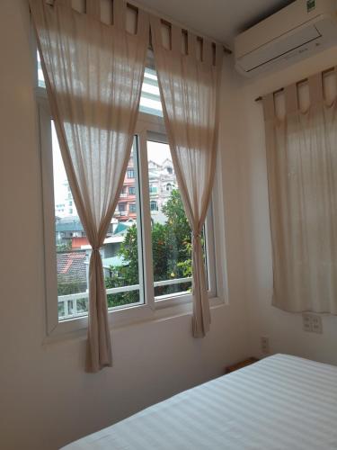 a bedroom with a bed and two windows with curtains at Tâm Homestay in Hue