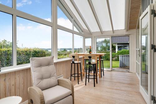 a conservatory with windows and a table and chairs at Beautiful Sea-View Holiday Home Near Ebeltoft Perfect For A Relaxing Stay By The Danish Coast in Ebeltoft