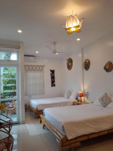 a bedroom with two beds and a chandelier at Tâm Homestay in Hue