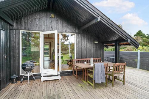 a house with a wooden deck with a table and chairs at Cottage Near St Sjørup For 6 People in Ørsted