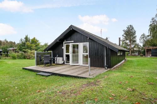 a black house with a deck in a field at Cottage Near St Sjørup For 6 People in Ørsted