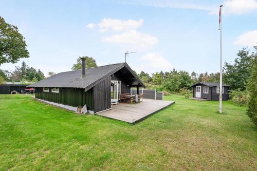 a cabin with a wooden deck in a field at Cottage Near St Sjørup For 6 People in Ørsted