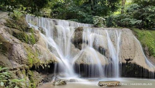 a waterfall in a park with water falling down at Hihotel Saraburi in Sara Buri