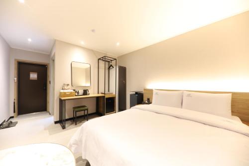 a bedroom with a white bed and a desk at Jeonju It's Hotel in Jeonju