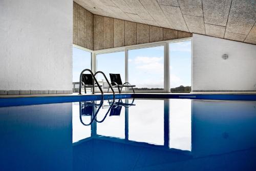 a swimming pool with two chairs in the water at Beautiful Home In Ebeltoft With Sauna, Swimming Pool And Wifi in Ebeltoft