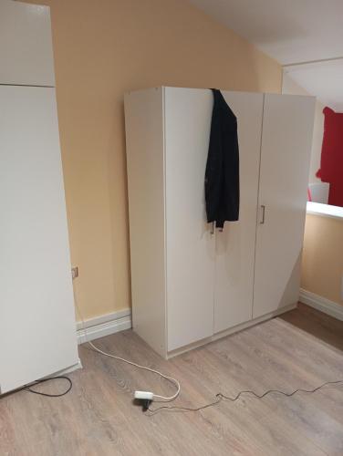 une armoire blanche avec une chemise noire suspendue sur elle dans l'établissement appartement, à Longeville-lès-Saint-Avold