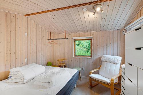 a bedroom with a bed and a chair and a window at Lovely Summer House In A Scenic Area Close To Ebeltoft in Ebeltoft