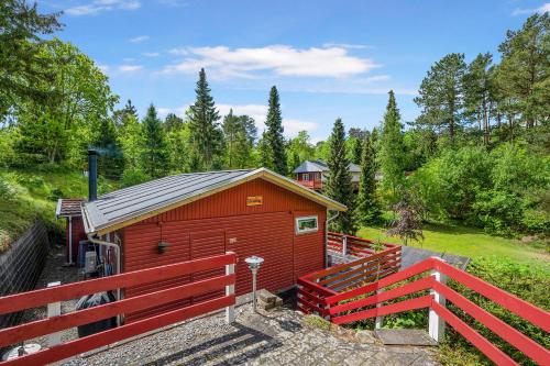 a red building with a fence next to a field at Lovely Summer House In A Scenic Area Close To Ebeltoft in Ebeltoft