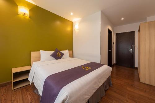 a bedroom with a large bed with a green wall at Azumaya Hotel Kim Ma 2 in Hanoi