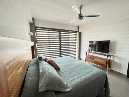 ヌエボ・バジャルタにあるNuevo Vallarta Condo nuevo y moderno a 5 min de playas PTRC17のベッドルーム(ベッド1台、天井ファン、テレビ付)