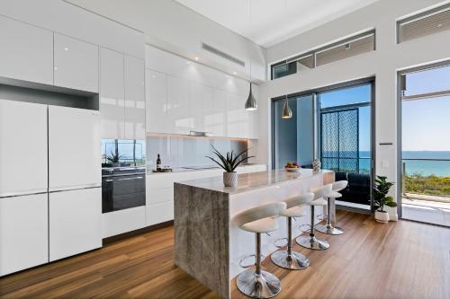 a kitchen with white cabinets and a counter with stools at Bokarina Beach Apartments, an Ascend Collection Hotel in Bokarina