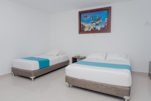 two beds sitting next to each other in a room at Hotel Aguamarina in Santa Marta