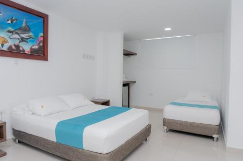 a bedroom with two beds and a painting on the wall at Hotel Aguamarina in Santa Marta