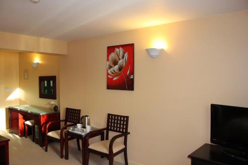 a living room with a table and chairs and a television at Desalis Hotel London Stansted in Elsenham