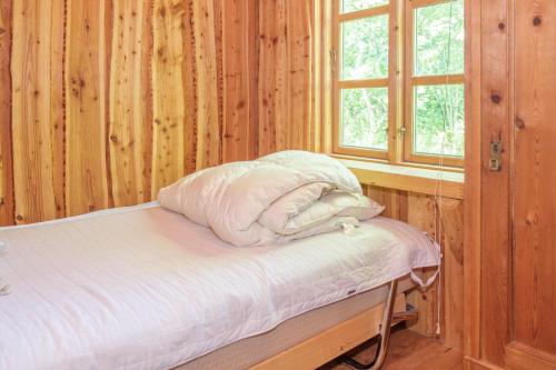 Ce lit se trouve dans un dortoir doté de murs en bois et d'une fenêtre. dans l'établissement Beautiful Home In Knebel With 2 Bedrooms, à Knebel