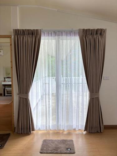 a large window with curtains and a rug on the floor at Siam Butterfly Farm in Ban Huai Salok