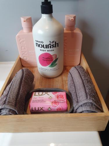 a wooden tray with a bottle of lotion and other products at The Red Shed in Matamata