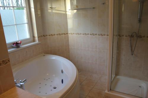 a bathroom with a white tub and a shower at Desalis Hotel London Stansted in Elsenham