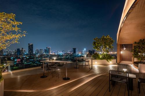 a rooftop deck with tables and chairs at night at Somerset Sukhumvit 71 Bangkok in Bangkok