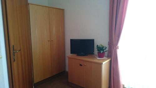 Zimmer mit TV auf einer Kommode mit Tür in der Unterkunft Pension und Berggasthaus Kapellenstein in Geyer
