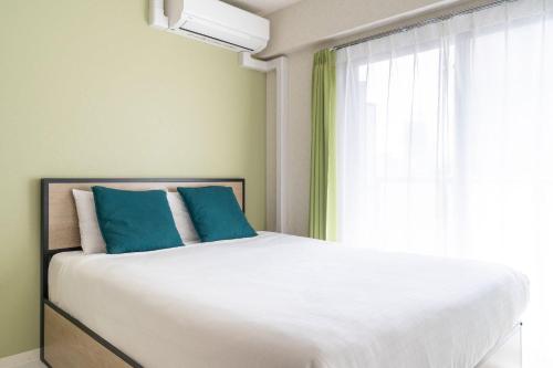 a bedroom with a bed with blue pillows and a window at Laurea Tower Ikebukuro in Tokyo
