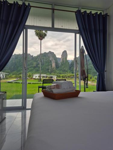 a bedroom with a bed with a view of a field at นัชชานามุงโฮมสเตย์ in Ban Mung