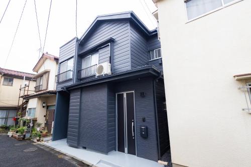 a black house with a door on a street at K's Casa西新井 駅徒歩4分 ディズニー車26分 56m2 ハンギングチェア 下町の快い暮らし in Tokyo