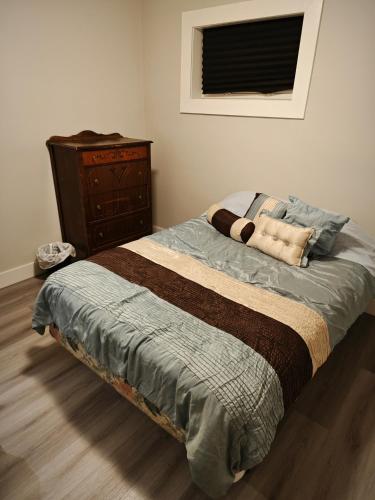 a bedroom with a bed with a dresser and a bed sidx sidx at Chamber Inn in Edmonton