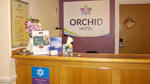 a counter with a hotel sign and flowers on it at Orchid Epsom; Sure Hotel Collection by Best Western in Epsom