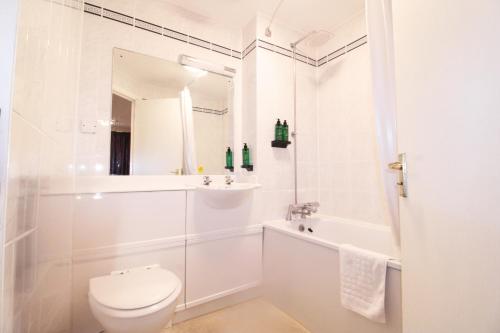 a white bathroom with a toilet and a tub and a sink at Orchid Epsom; Sure Hotel Collection by Best Western in Epsom