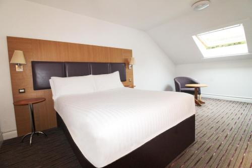 a bedroom with a large white bed and a chair at Orchid Epsom; Sure Hotel Collection by Best Western in Epsom