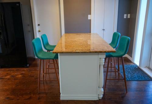 a white island with green bar stools in a room at Artsy Bohemian - 2 Min to Airport -TheGoodPlace#2 in San Antonio