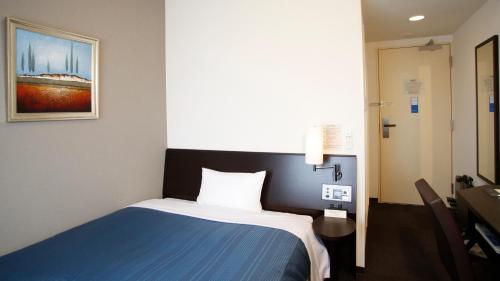 a bedroom with a blue and white bed in a room at Hotel Route-Inn Ishinomaki Kanan Inter in Ishinomaki