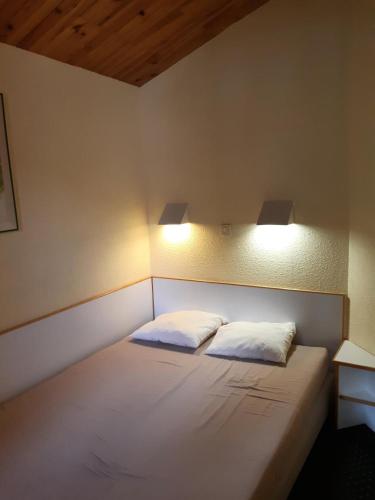 Ce lit se trouve dans un dortoir doté de 2 oreillers blancs. dans l'établissement Résidence Le Sextant - maeva Home - 2 Pièces 5 Personnes Confort MAE-4595, à La Plagne Tarentaise