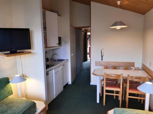 Cette petite chambre comprend une cuisine et une table avec des chaises. dans l'établissement Résidence Le Sextant - maeva Home - 2 Pièces 5 Personnes Confort MAE-4595, à La Plagne Tarentaise