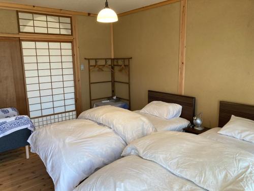 a room with four beds with white sheets at 小舞庵 Komaian in Tokushima