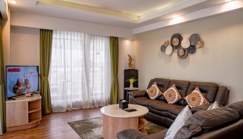 a living room with a couch and a tv at Grand Sunshine Resort & Convention in Bandung